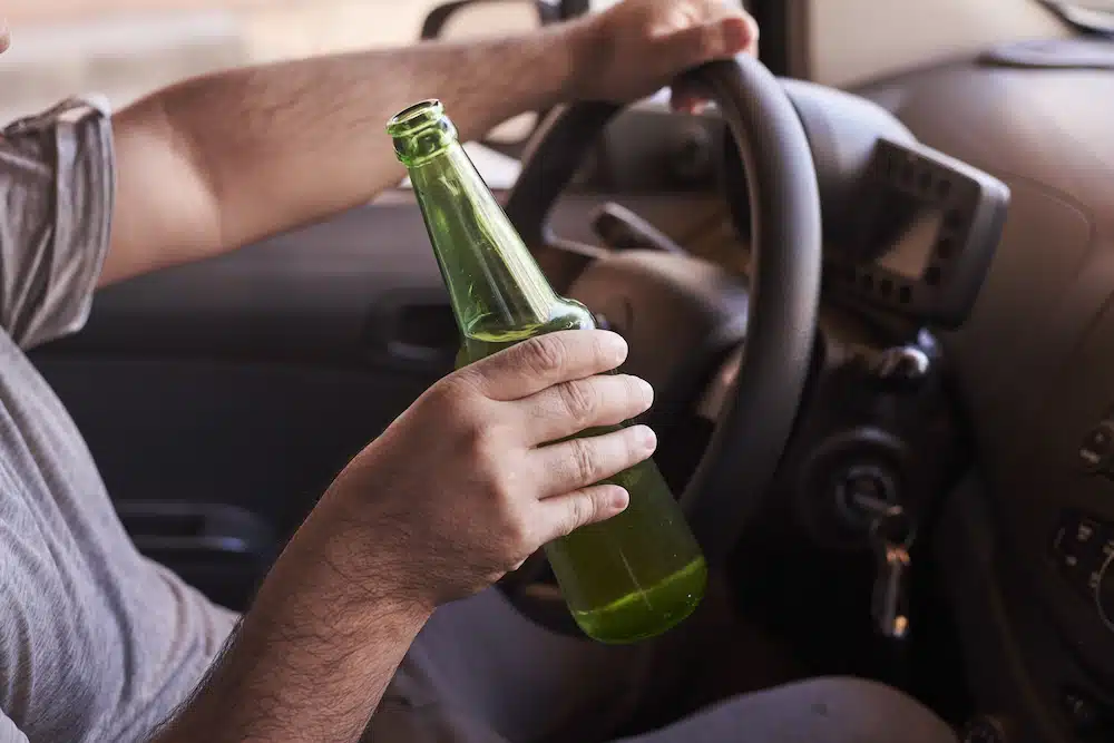 A man holding bottle in car while driving