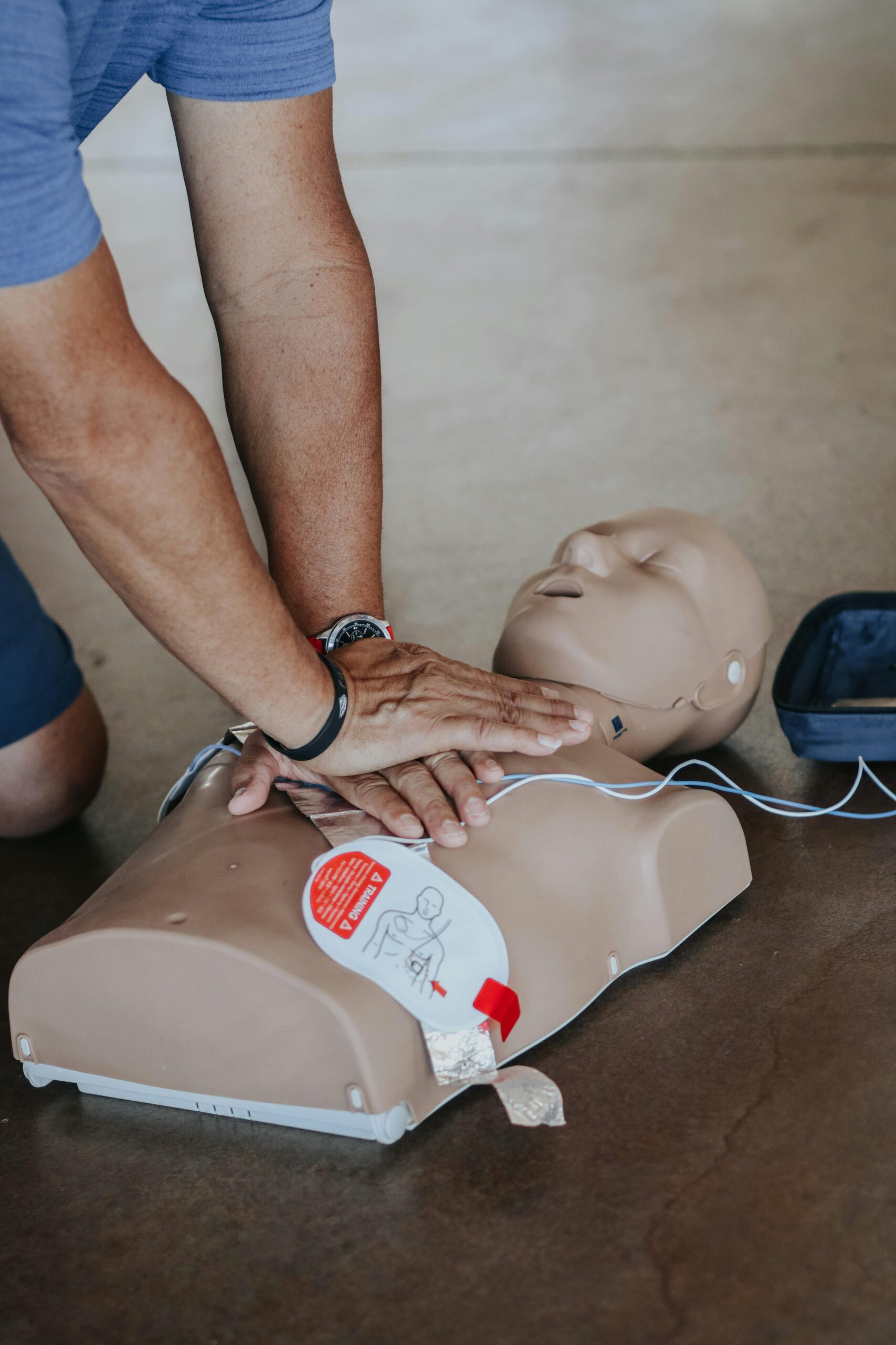 Person performing CPR on a dummy with AED