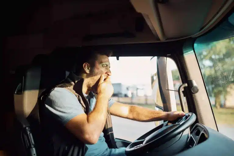 Man Driving Truck with Hand to Face yawning