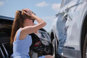 A woman on the phone, examining the damage of a car accident in Louisiana, wondering how fault is determined.