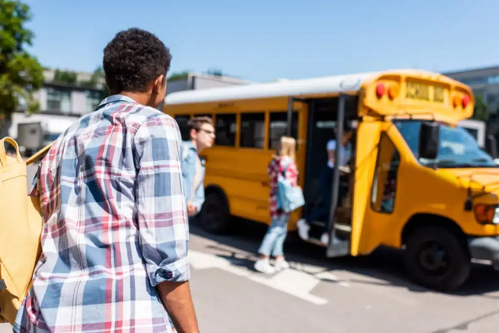rear-view-of-teen-african-american-schoolboy-walking to a school bus