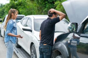 A man and woman looking at the hood of their car after a car accident. What are my rights as a victim of a DUI accident in New Orleans