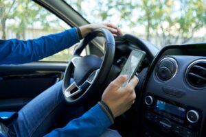 A man texting while driving. What are common causes of distracted driving car accidents?