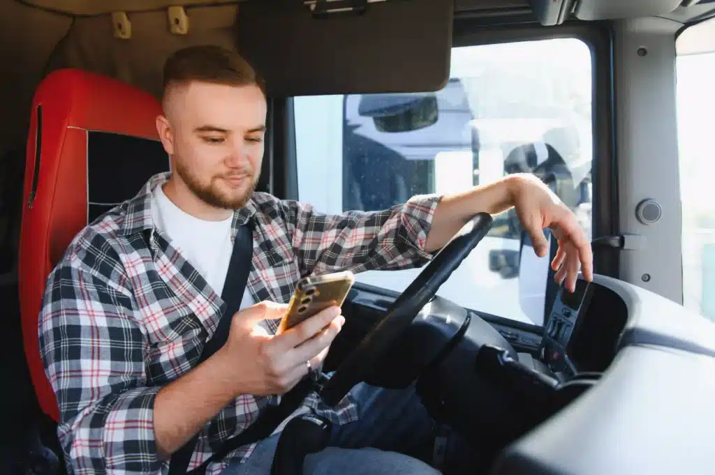 Young Male Truck Driver Checking His Smartphone while driving