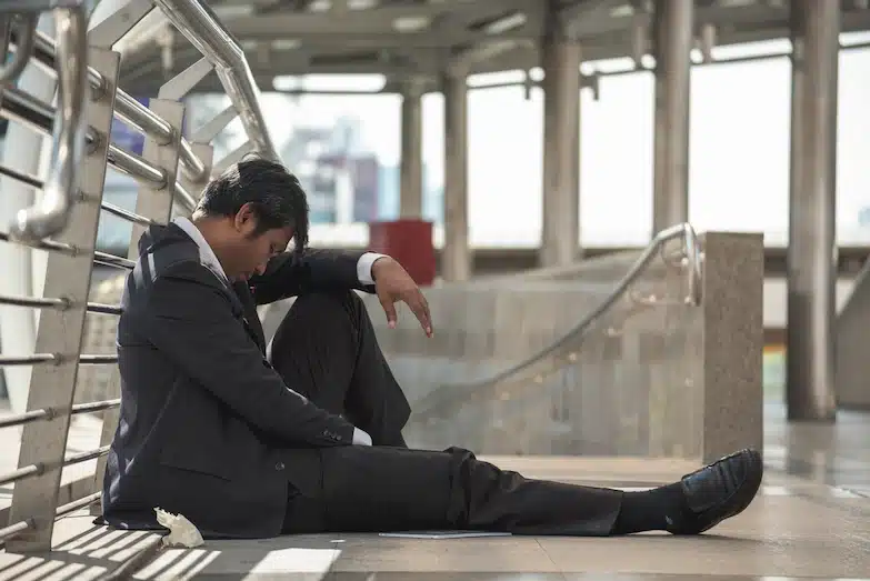 business man sitting exhausted on city walkway