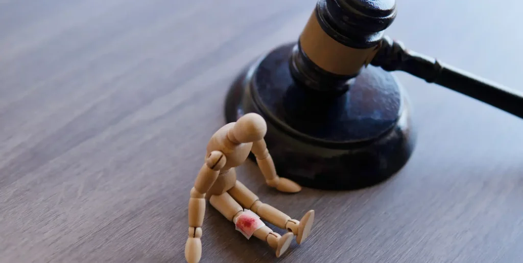 hurt-mannequin-with-gavel-on-wooden-table-