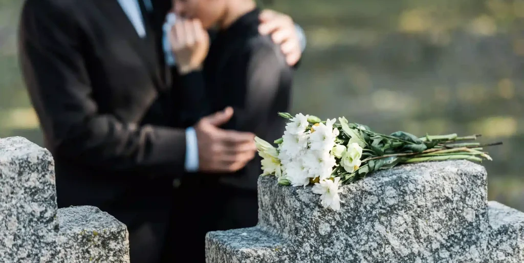 mourning-couple-at-grave-with-flowers-bouquet-