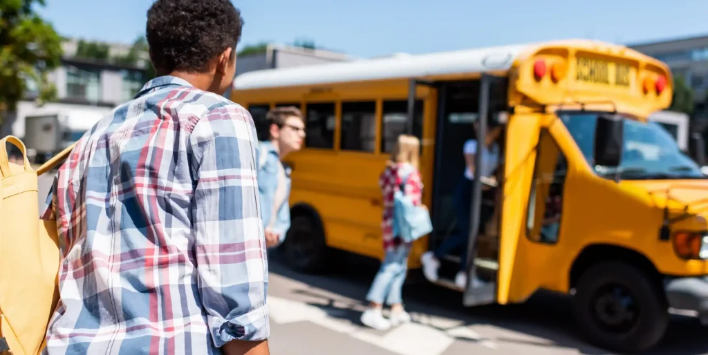 rear-view-of-teen-african-american-schoolboy-walking to a school bus