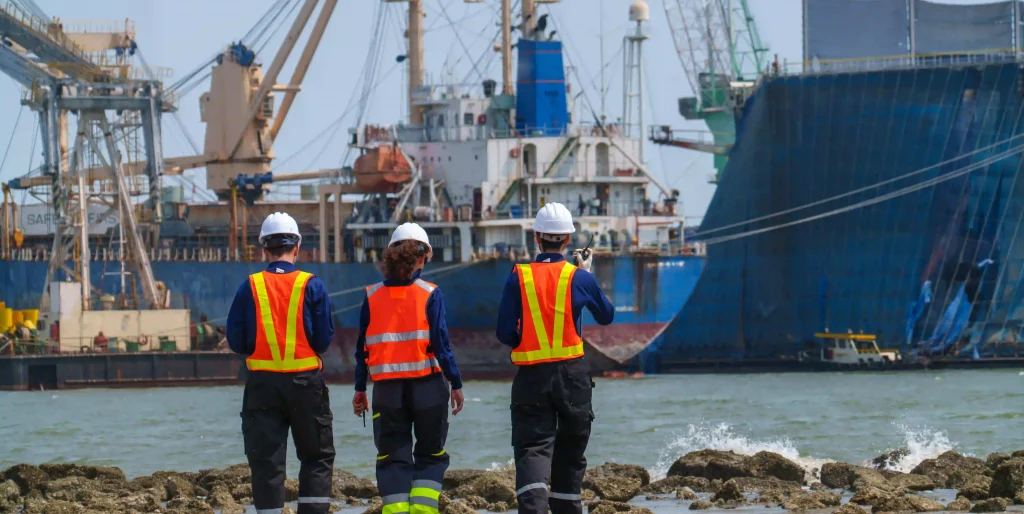 workers-walk-along-the-shore-near-ships-and-machin-