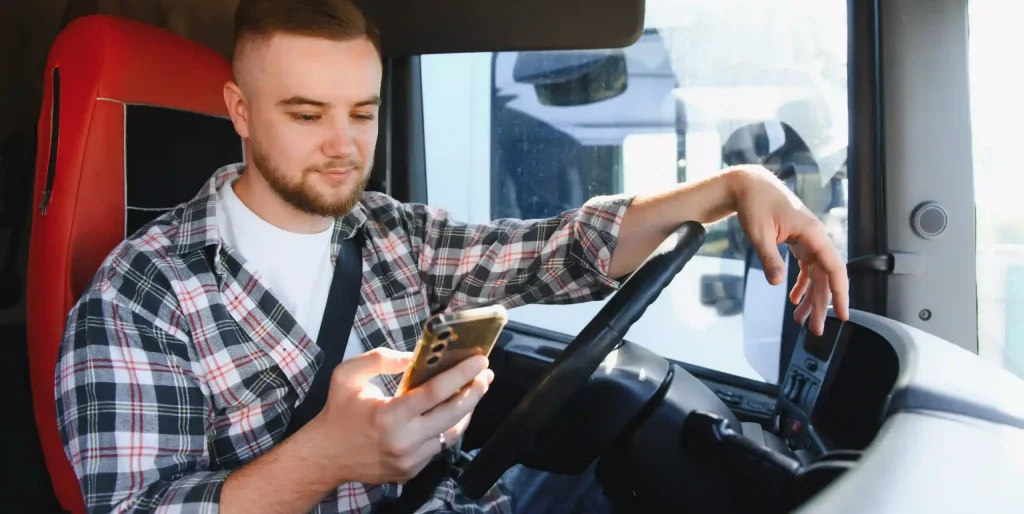 Young Male Truck Driver Checking His Smartphone while driving